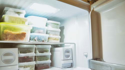 binnenkant van een vriezer met bevroren voedingsmiddelen in bakjes opgestapeld